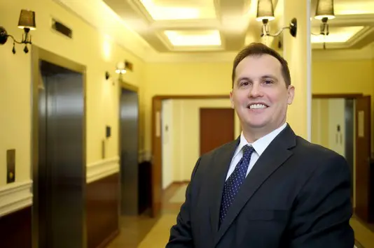 A man in suit and tie standing next to an elevator.