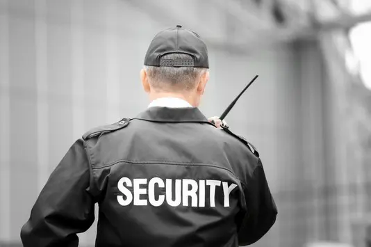 A security guard is holding a black stick.