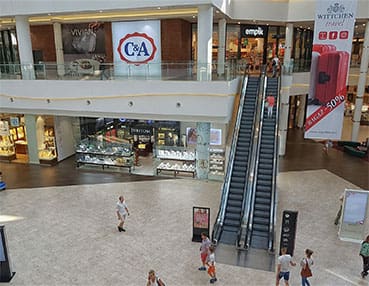 A mall with people walking around and escalators