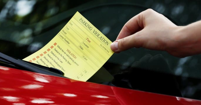A person is holding onto a parking violation ticket.